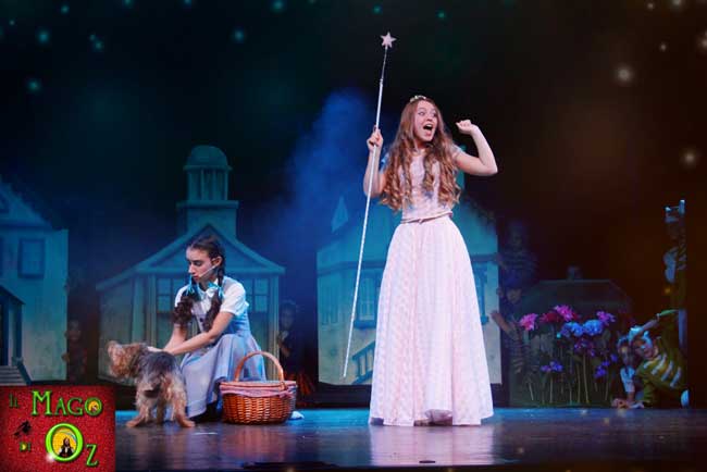Una scena del musical Il Mago di Oz: i Mastichini ridono perchè Dorothy dice che "le streghe sono brutte, con i porri sul naso e sul mento" ma non sa che anche la bella Glinda è una Strega, la Strega buona del Nord