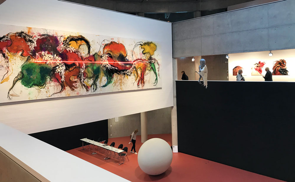 Uno scorcio della mostra al TAM – Sulla parete: Koen Vanmechelen, NO TITILE (PAINTING), 2019; al piano terra: IN BETWEEN, 2018, scultura in poliestere – Photo: MaSeDomani Uno scorcio della mostra The Worth of Life - Sulla parete: NO TITILE (PAINTING), 2019; al piano terra: IN BETWEEN, 2018, scultura in poliestere - Photo: MaSeDomani
